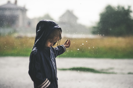 Little Girl Playing Alone Outside in Summer Rain